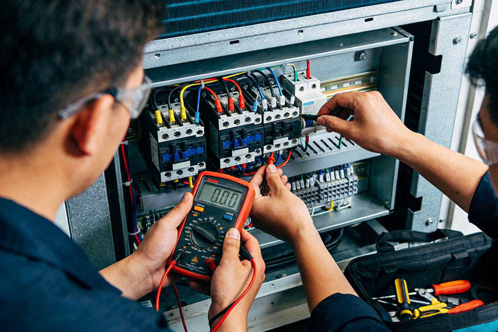 Technicians testing electrical equipment connections.